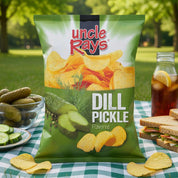 Bag of Uncle Ray's Dill Pickle flavored chips on a picnic table with pickles and sandwiches.
