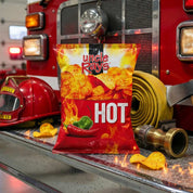 Bag of Uncle Ray's Hot chips on a fire truck with a helmet and hose in the background.
